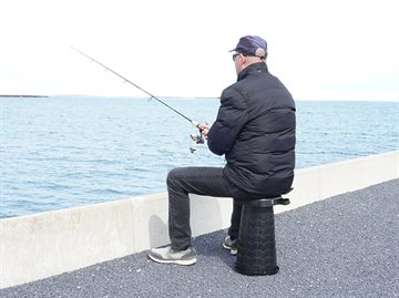 Mand der fisker og sidder på den foldbare teleskopstol
